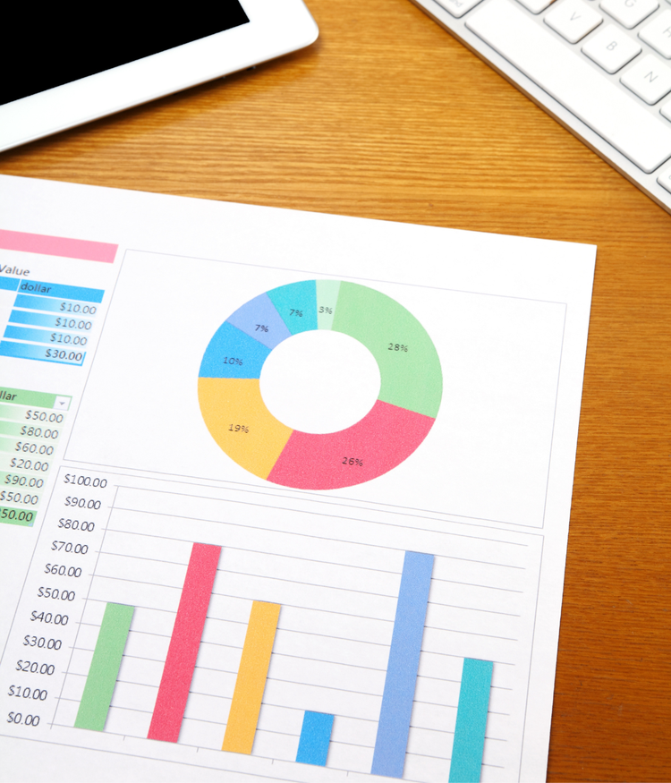 Printed financial charts on paper with keyboard and tablet nearby.