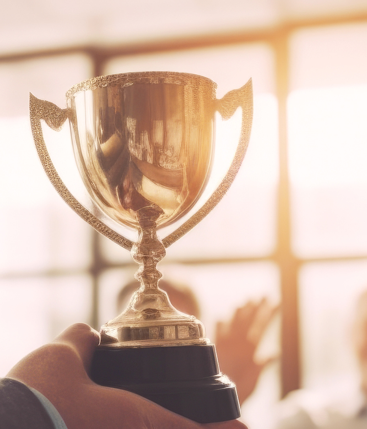 A person holding a trophy against a bright background.